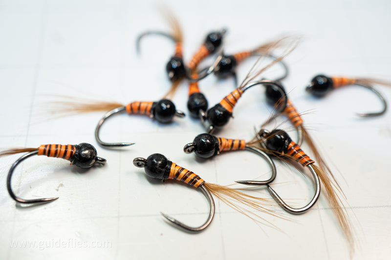 synthetic orange body and a heavy tungsten bead head with an oversized comp hook