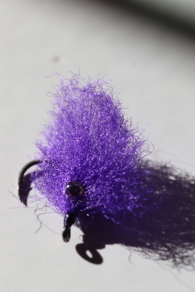 Saltwater fly of colored purple with beaded eyes with a size 1 umpqua hook that are great for catching tarpon