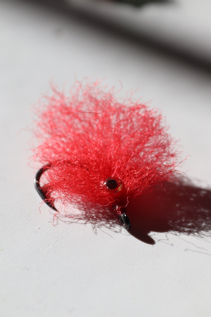 Saltwater fly of colored red with beaded eyes with a size 1 umpqua hook that are great for catching tarpon 